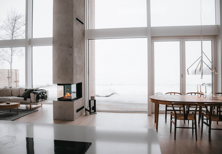 Holz-Kamineinsatz VISIO 3:1 trennt als Raumteiler Esszimmer und Wohnzimmer in einem modernen Haus im Norden