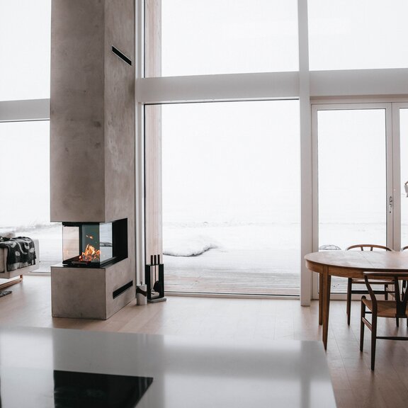 Holz-Kamineinsatz VISIO 3:1 trennt als Raumteiler Esszimmer und Wohnzimmer in einem modernen Haus im Norden