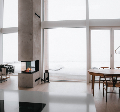 Holz-Kamineinsatz VISIO 3:1 trennt als Raumteiler Esszimmer und Wohnzimmer in einem modernen Haus im Norden