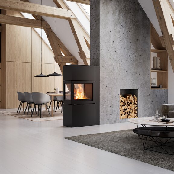 Kaminofen 600 RD in der Farbe schwarz im hellen und modernen Wohnzimmer mit Holzelementen und Betonwand