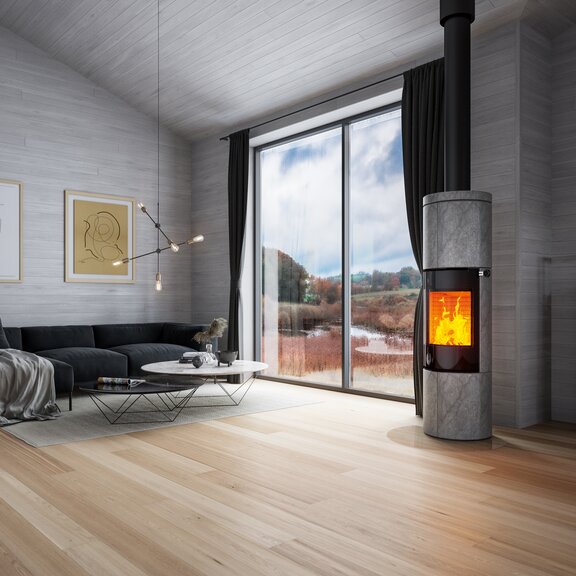 Holz-Kaminofen JUNO 166 L mit Specksteinverkleidung und Vollglas-Feuerraumtür in grossem Wohnzimmer in Grautönen