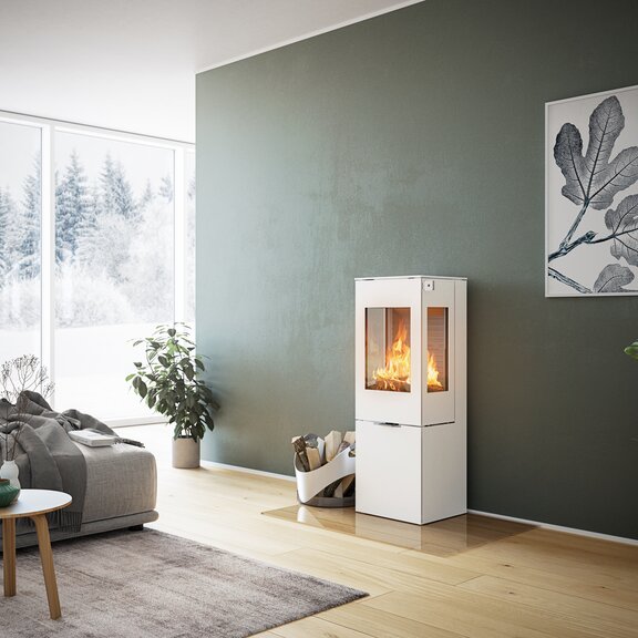 Holz-Kaminofen NEXO 120 in Weiss mit Stahltür und zwei Seitenfenstern vor grüner Wand in dekorativem Wohnraum
