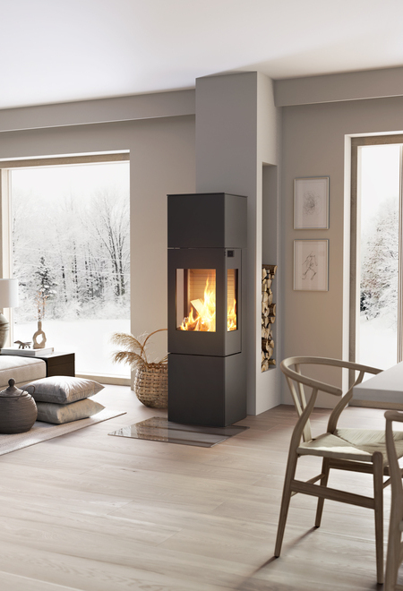 Holz-Kaminofen NEXO 160 in Schwarz mit Stahltür und Seitenfenster mitten im Wohnraum zwischen Esszimmer und Wohnzimmer