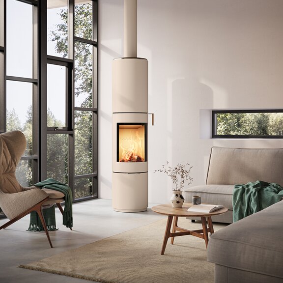 Kaminofen PILAR in Sand mit Stahltüre und Eichenholz Türgriff im modernen Wohnraum mit grosser Fensterfront