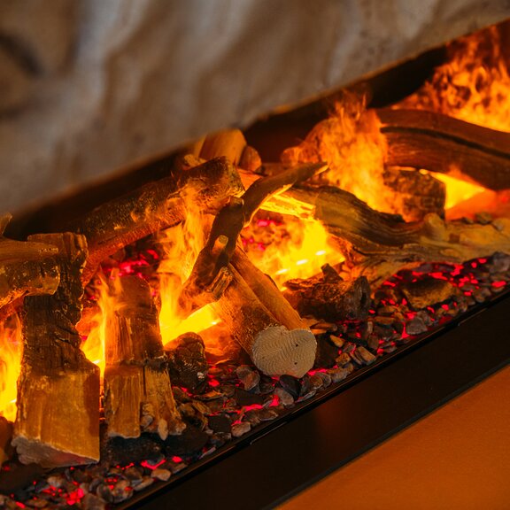 Die Holzscheite und Wasserdampfflammen werden mit LED Lampen beleuchtet um ein Elektrofeuer zu erzeugen.