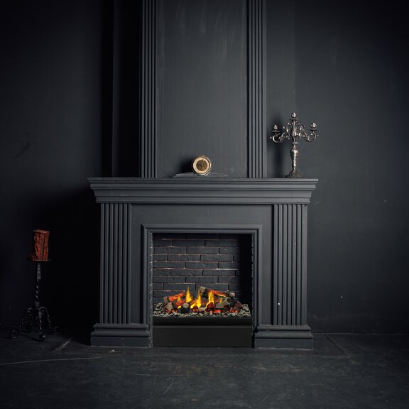 Das elektrische Effektfeuer Juneau wurde in einen stillgelegten Kamin aus schwarzem Stein verbaut.