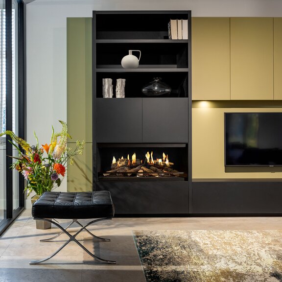 Der Elektrokamin E-One 100 Front im Wohnzimmer als Teil eines grünen Sideboard mit integriertem Fernseher.