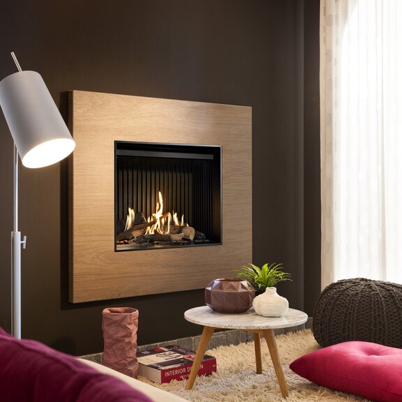 Gas-Kamin G60/48F Frontversion mit Holzumrahmung an dunkler Wand eingebaut im Wohnzimmer