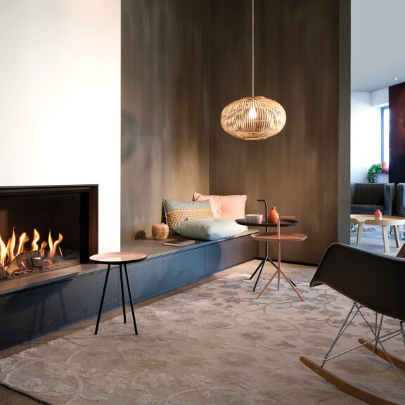 Gas-Kamin G80/48F auf dunklem Sockel mit weisser Verkleidung im klassischen Wohnzimmer mit brauner Wand und Teppich