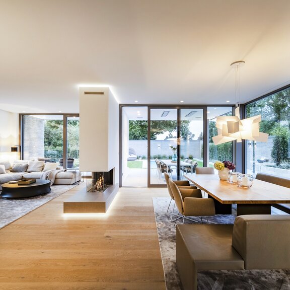 Der Gas-Kamin GP85/50R mit weisser Verkleidung fungiert als Raumteiler zwischen Essbereich und Wohnzimmer.