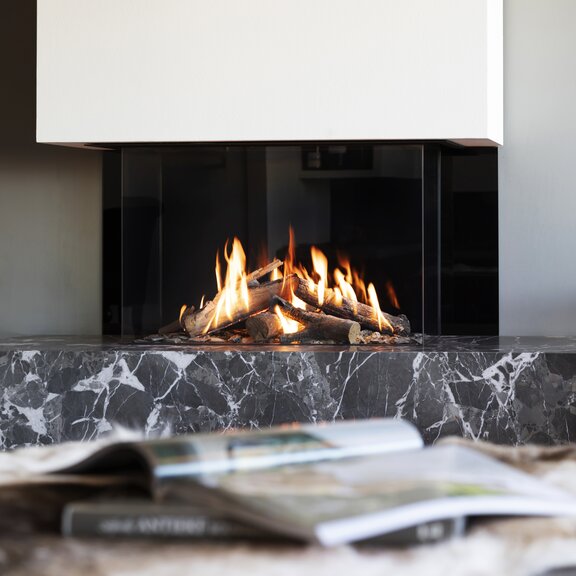 Gas-Kamin GP85/55S dreiseitig verglast auf Steinaufsatz im Wohnzimmer