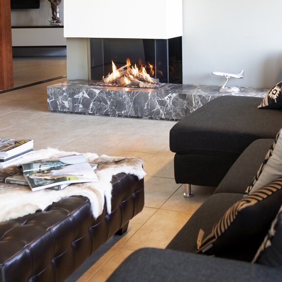 Gas-Kamin GP85/55S dreiseitig verglast im schlichten Wohnzimmer mit Sofa und Kissen