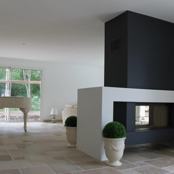 Holz-Kamin W105/47T von Kalfire in Tunnelversion ohne Feuer in einem klassisch eingerichteten Wohnzimmer mit Flügel und verzierten Pflanzentöpfen