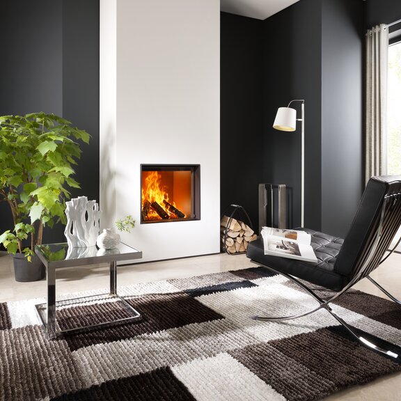 Holz-Kamin W60/51F von Kalfire symmetrisch eingebaut in einer weiss gestrichenen Wand in modern eingerichtetem Wohnraum