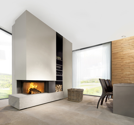 Holz-Kamin W65/38C von Kalfire. Der zweiseitige Kamin (links) ist in einer beigefarbenen Zwischenwand eingebaut und steht auf einer modernen Bank aus Naturstein